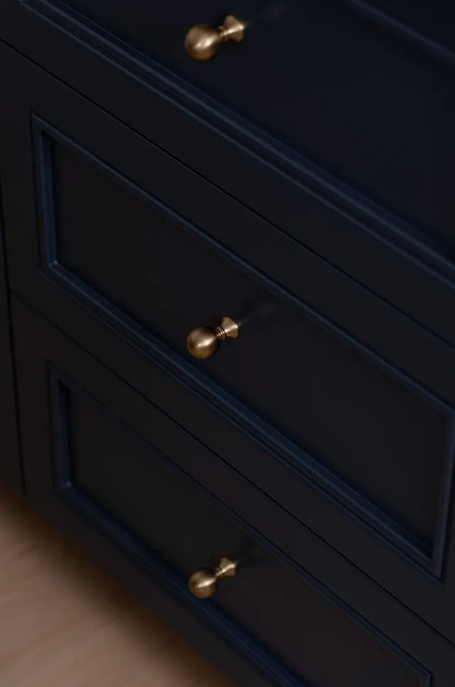 Close-up of round brass knobs on the navy shaker drawers