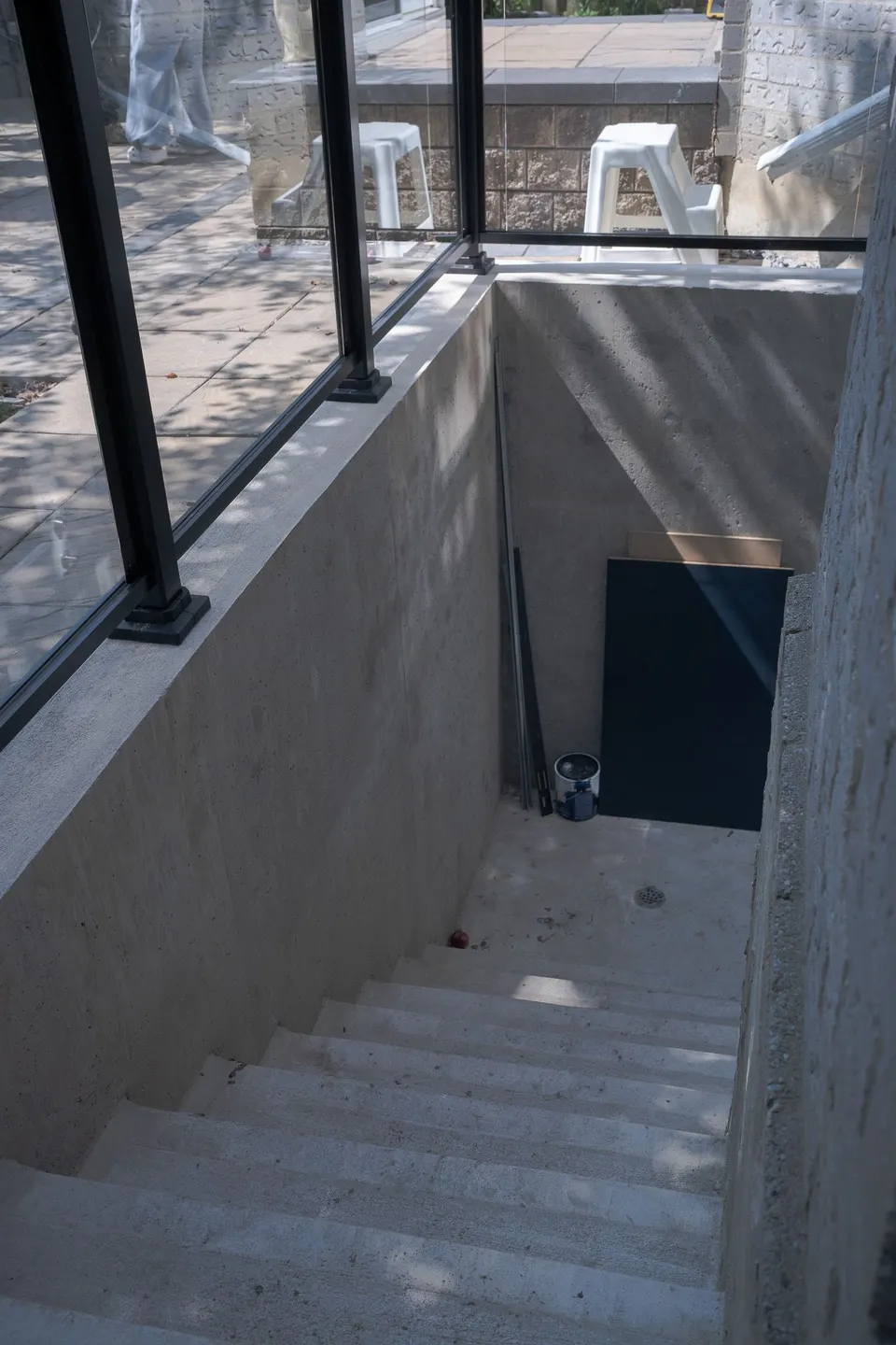 A private walk-up entrance to a basement suite: concrete stairs behind a black-framed glass guard