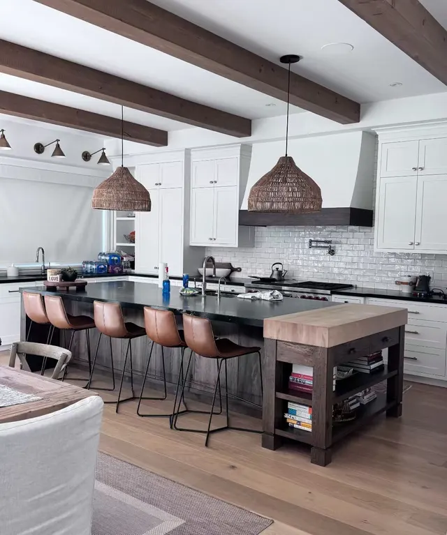 Beamed kitchen with leather stools at a black island and a butcher-block end