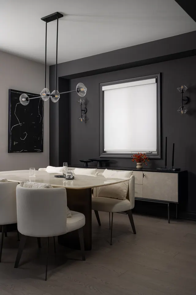 Dining room with charcoal walls, cream upholstered chairs and a globe chandelier