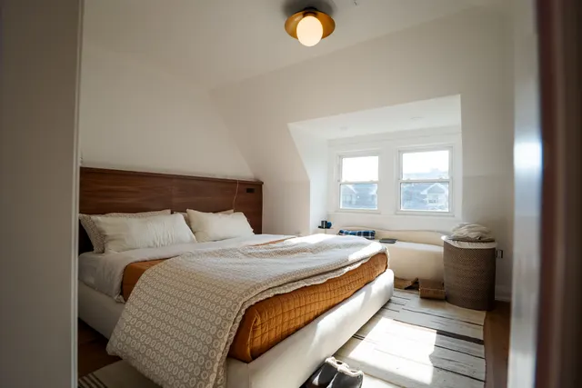 Sunlit third-floor bedroom under a sloped ceiling with built-in wardrobes