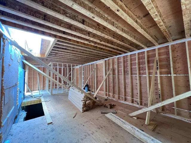 Inside the framed shell of a new addition: stud walls, open joists and a subfloor