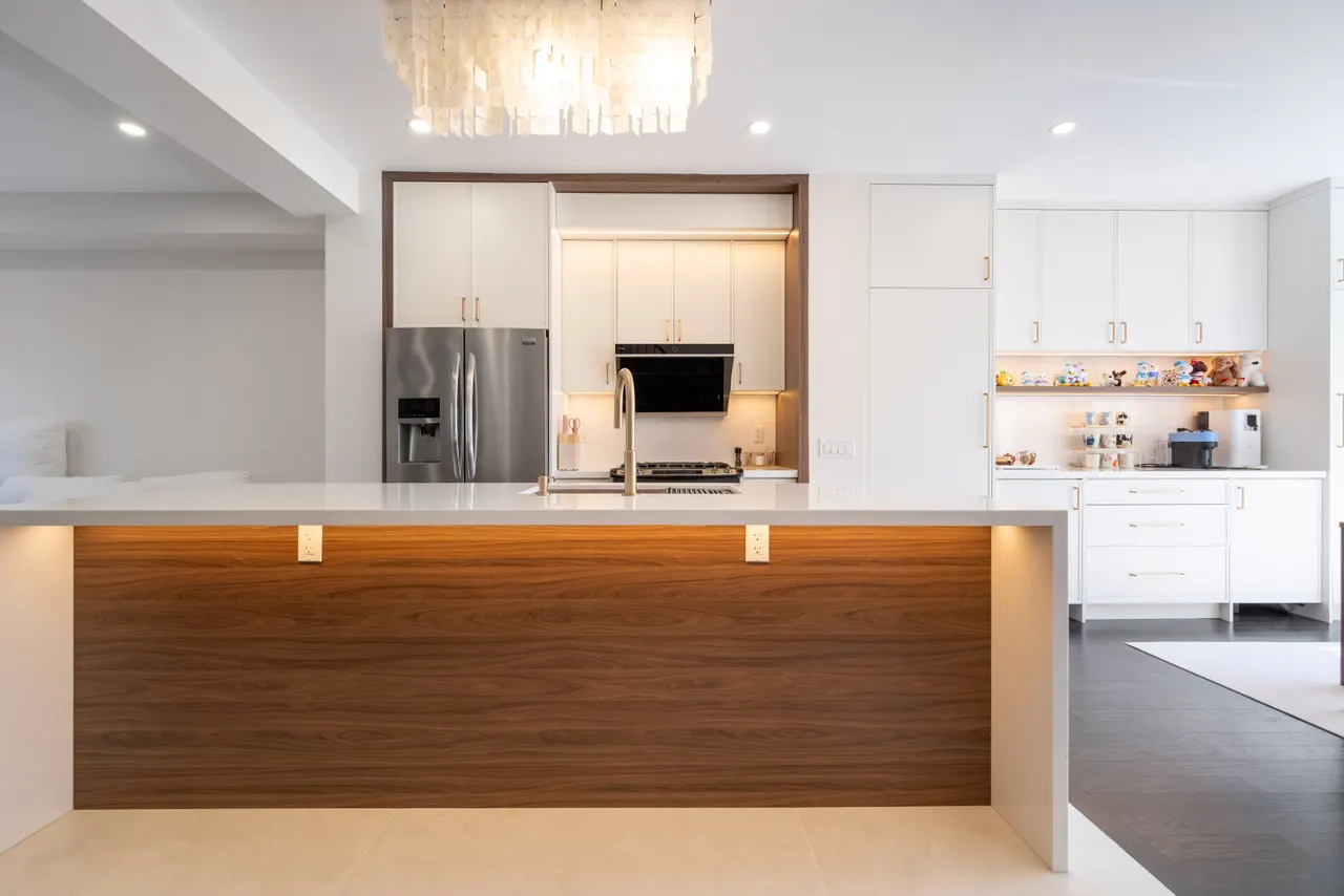 A townhouse kitchen with warm white cabinetry and a walnut-panelled island with waterfall quartz ends