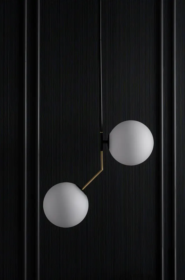 Close-up of a two-globe brass pendant against the fluted black panelling