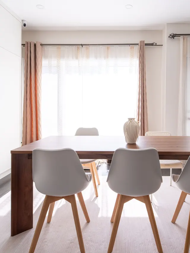 Walnut dining table and white chairs under a curtained window
