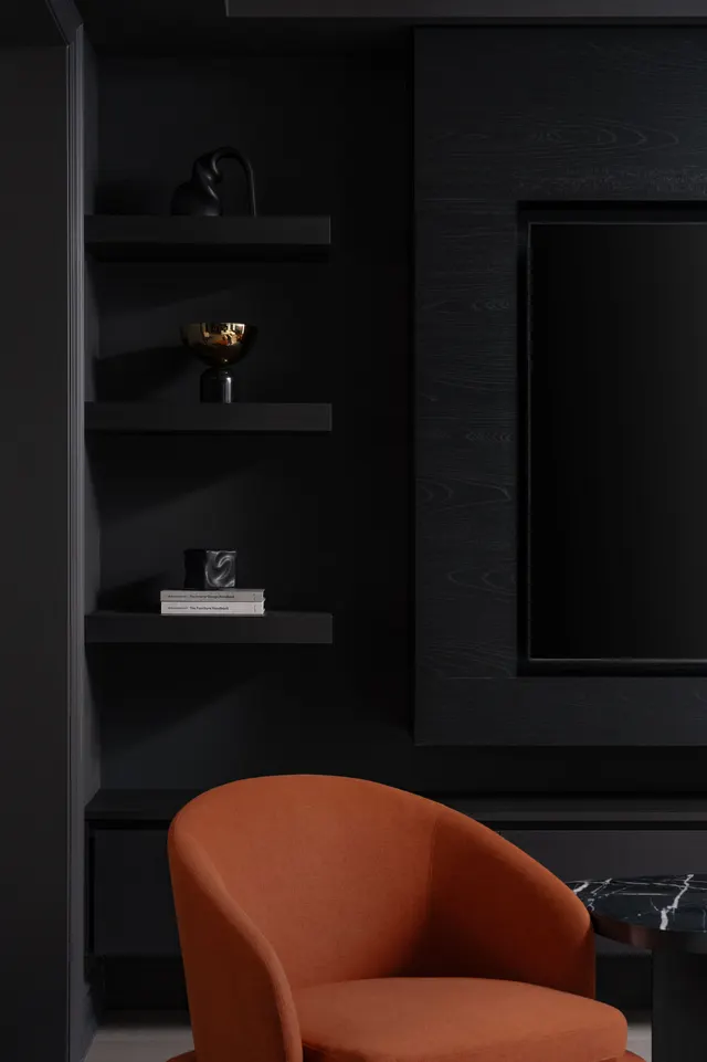 A cognac armchair beside black open shelving and a dark wall panel