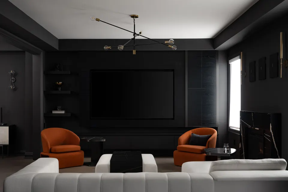 Charcoal living room with two cognac armchairs, a white sectional, a black coffee table and dark open shelving