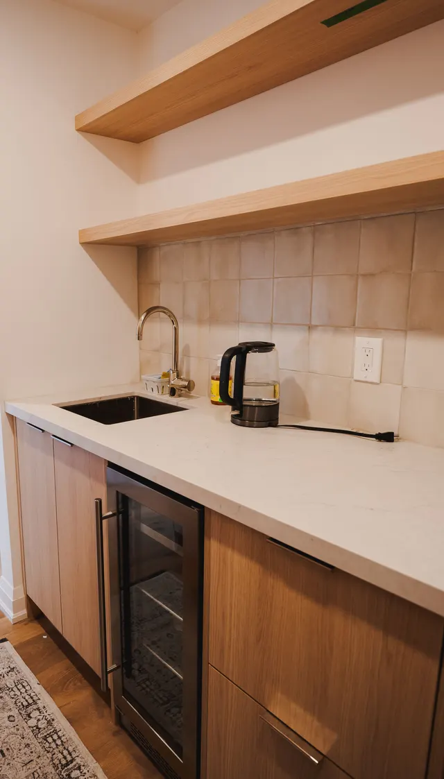 Open oak shelves over a gooseneck faucet, stone counter and glass-door fridge