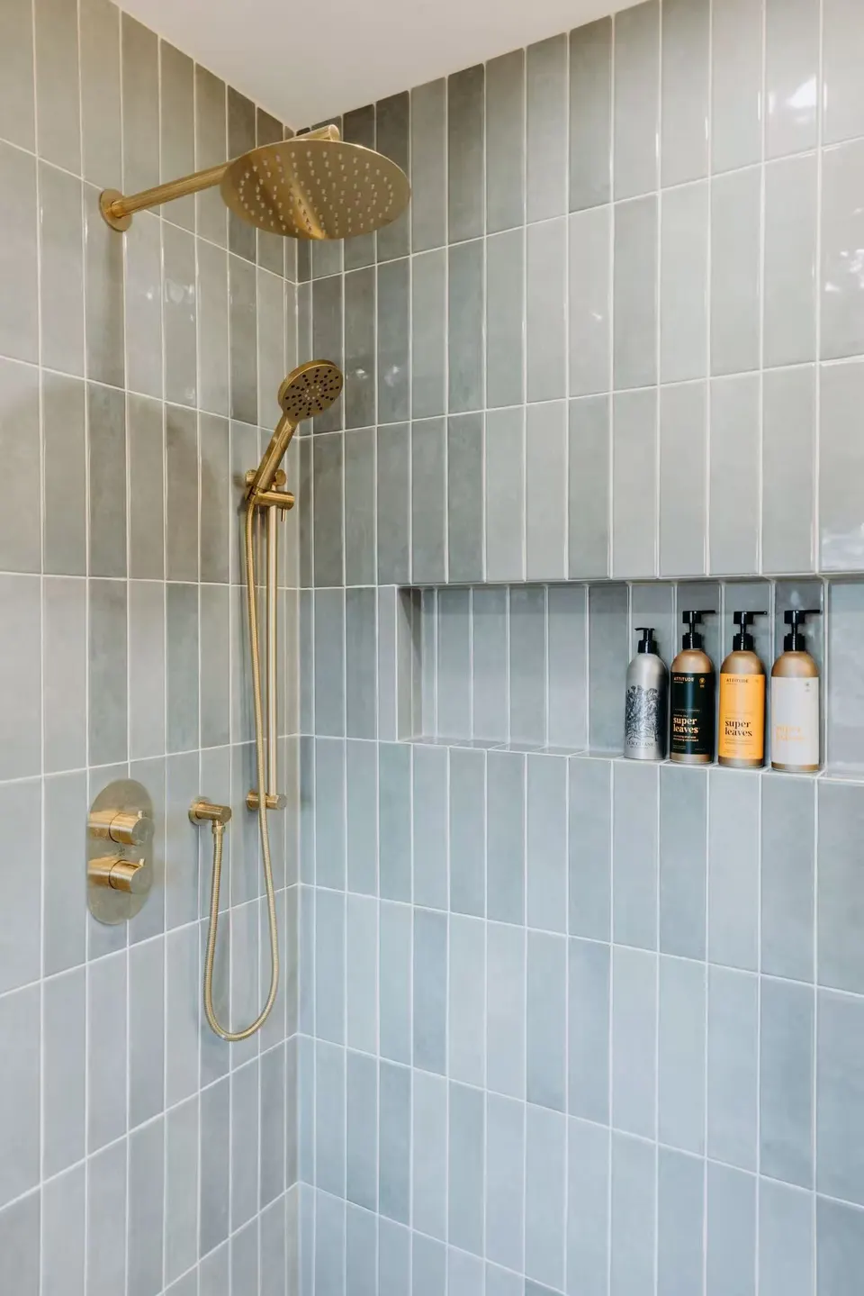 Handcrafted green wall tile with a brushed-gold hand shower and a recessed niche
