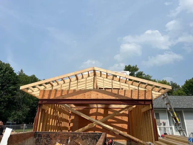 Roof trusses set on the framed walls of a new addition against a blue sky