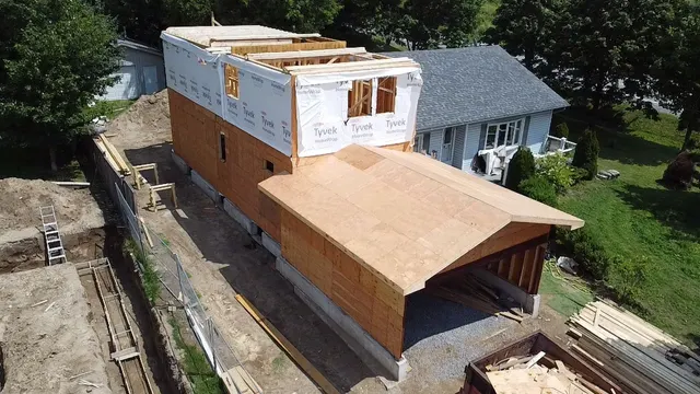 Aerial view of an addition sheathed to its upper storey above the original roofline