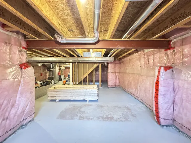 Basement before finishing: insulation and vapour barrier on the walls, a steel beam across the open joists