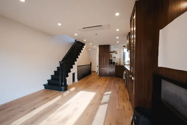 An opened-up main floor in a century home: a new black stair, a walnut kitchen wall and wide-plank oak floors