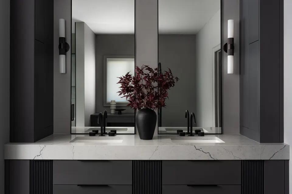 Charcoal double vanity with a white marble top, black faucets, a wide mirror and black wall sconces