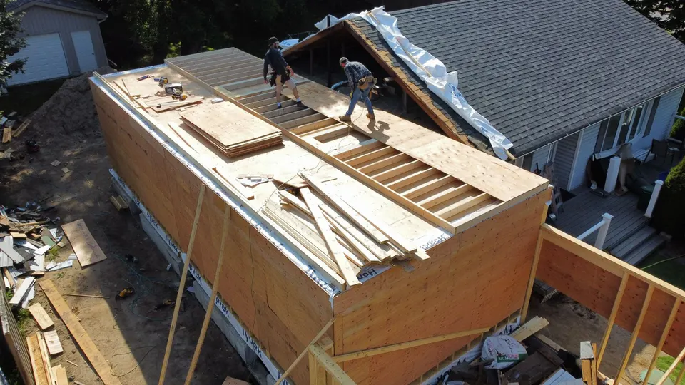 Aerial view of the addition framed in timber against the side of the house, walls up and roof framing started