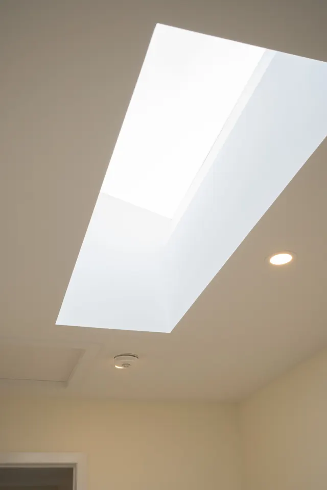 A skylight set into the white ceiling of the new addition, beside a pot light