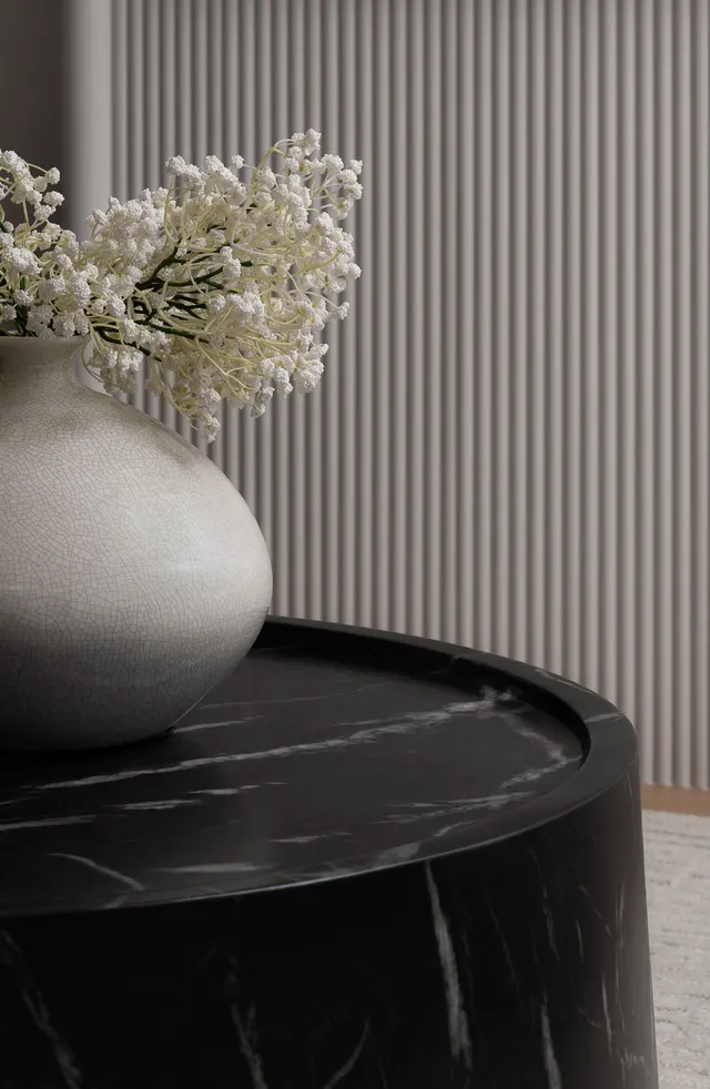 White vase of baby’s breath on a black marble side table against a fluted wall panel