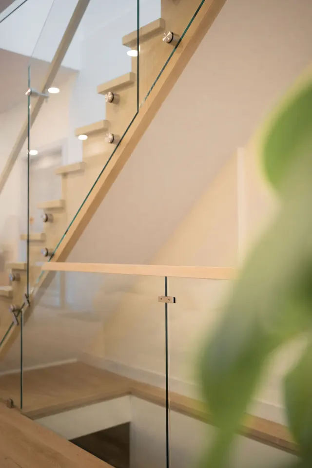 Inside the finished addition: an oak stair with a frameless glass guard and an oak handrail