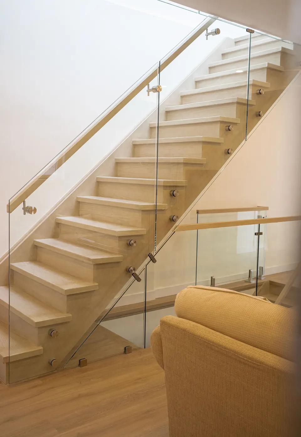 An open oak staircase with a glass guard and oak handrail inside a finished addition